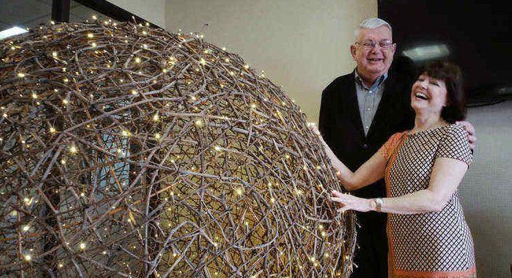 Roger Neathawk and Susan Dubuque smiling beside a large openwork sculpture