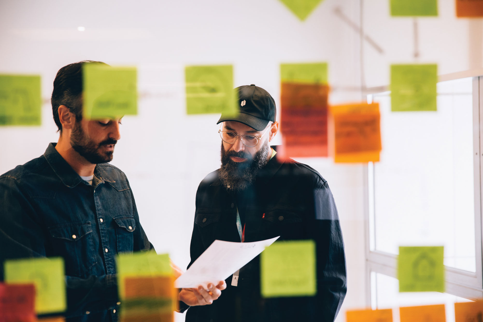 Roger Volodarsky, right, and a colleague review a document behind a wall of colored sticky notes