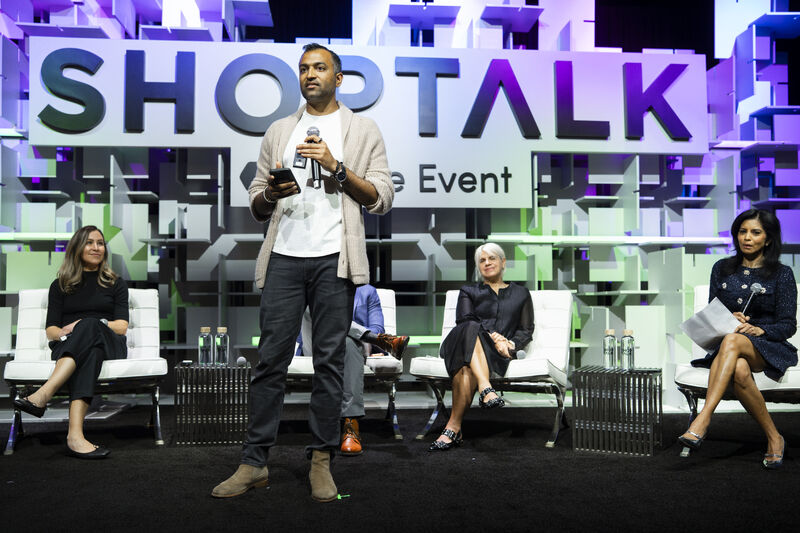 Rohan Shah speaking onstage at Shoptalk with fellow panelists seated behind him