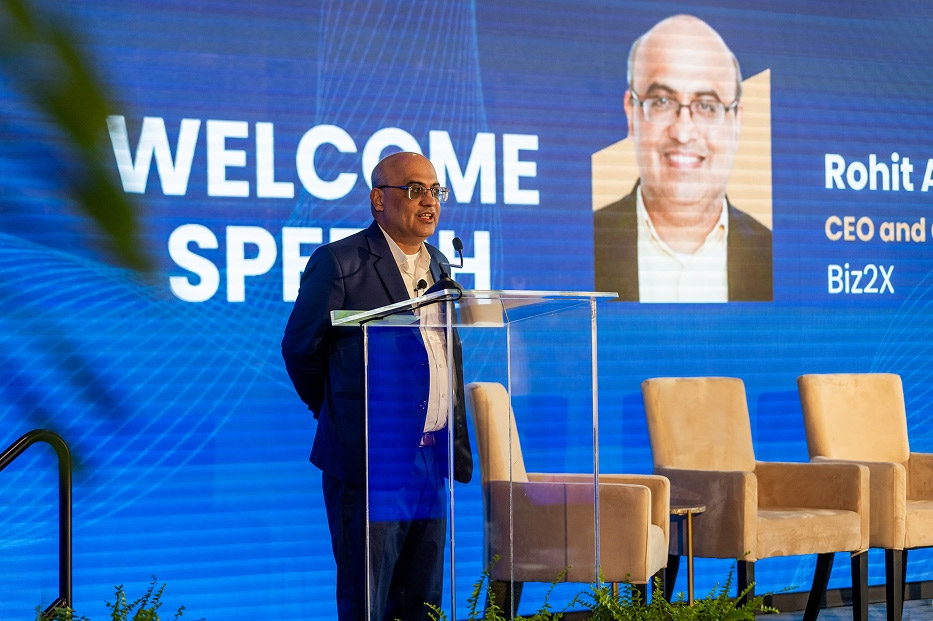 Rohit Arora speaking from a lectern at a Biz2X event
