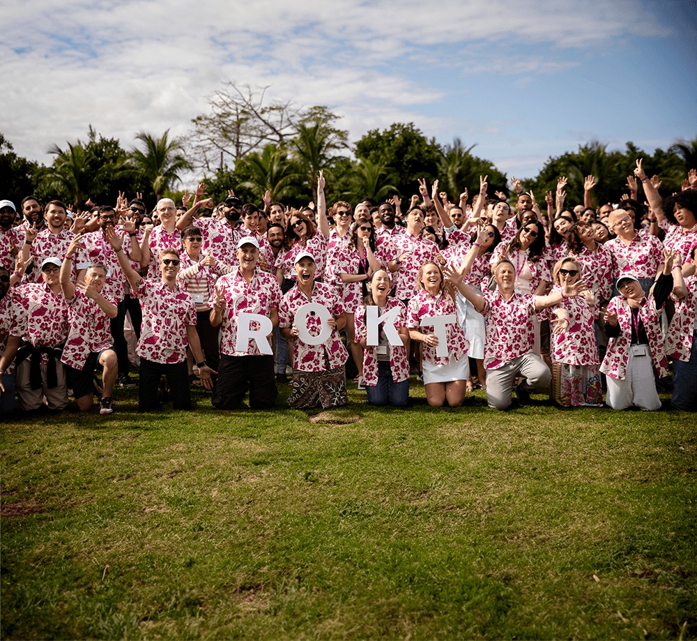 Rokt colleagues gathered outdoors in matching floral shirts at a global kickoff
