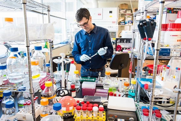 Roland Green working with pipettes at a crowded laboratory bench in Madison