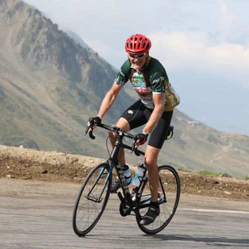 Ron Elwell cycling on a mountain road, wearing a red helmet