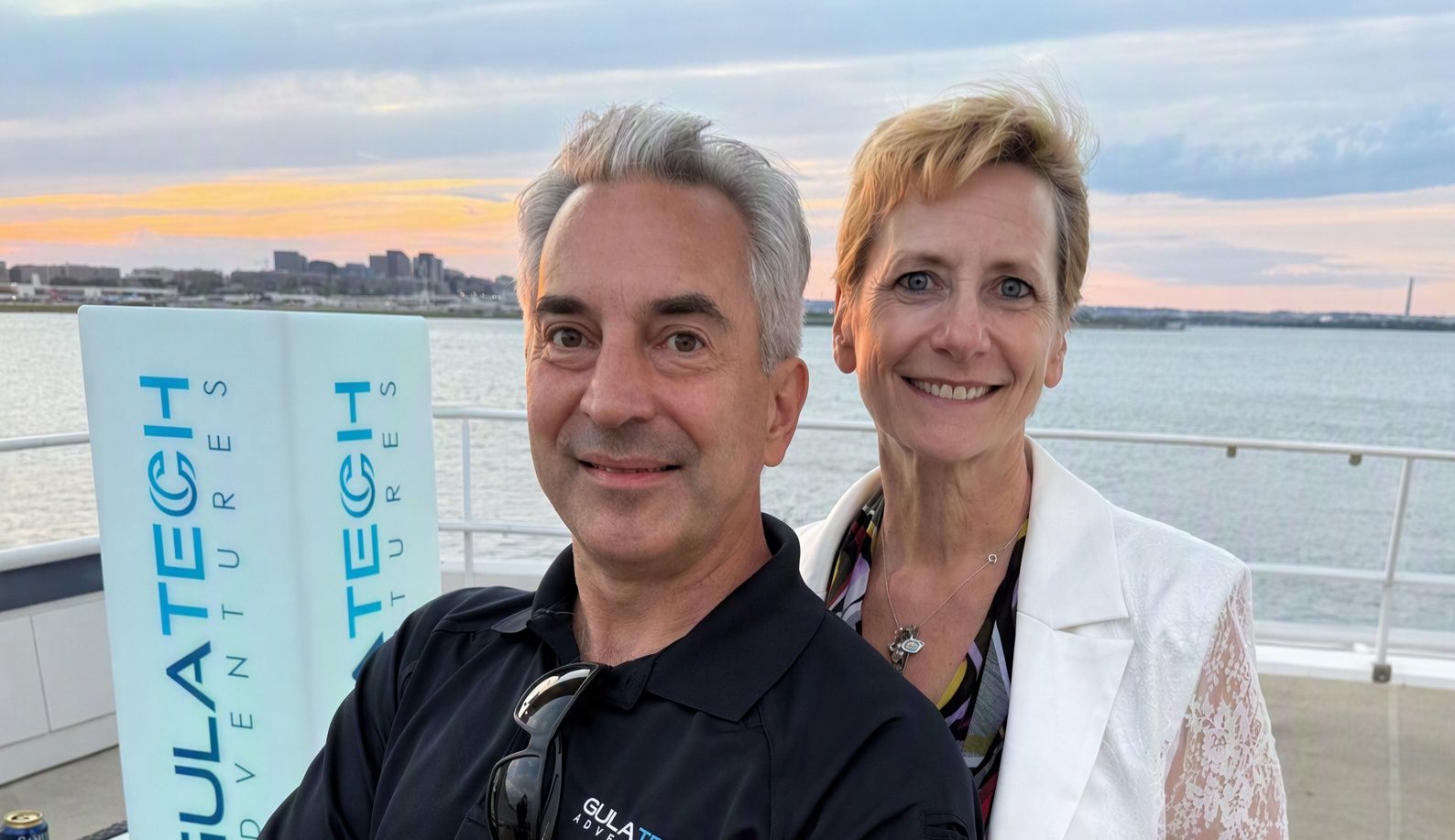 Ron and Cyndi Gula together on a boat, with water and a city skyline behind them