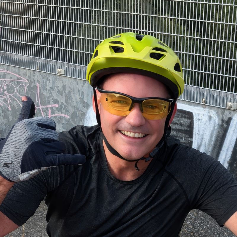 Oliver Bradley wearing a cycling helmet and glasses, giving a thumbs-up