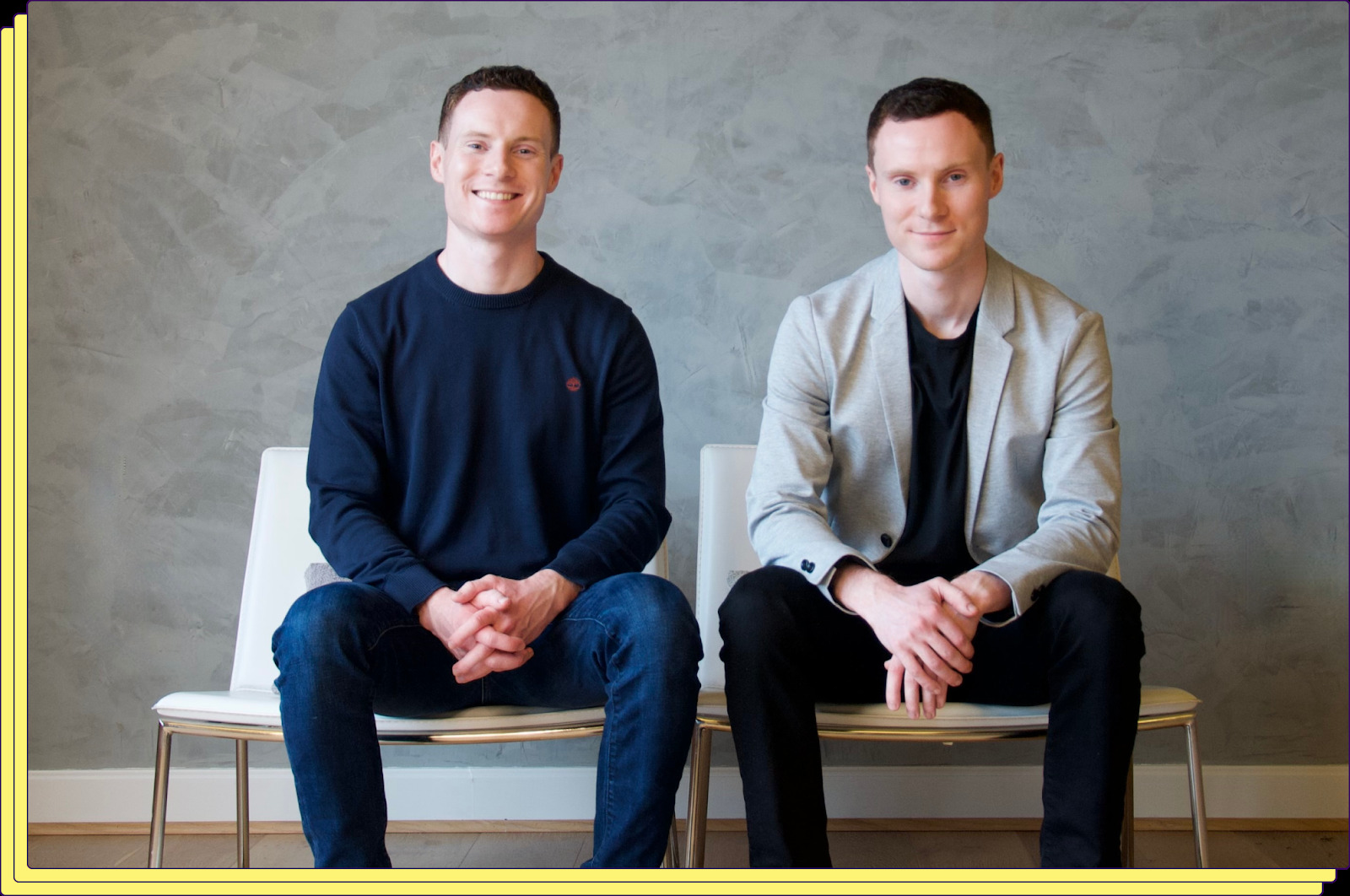 Conor and Ronan Burke seated together in front of a textured wall