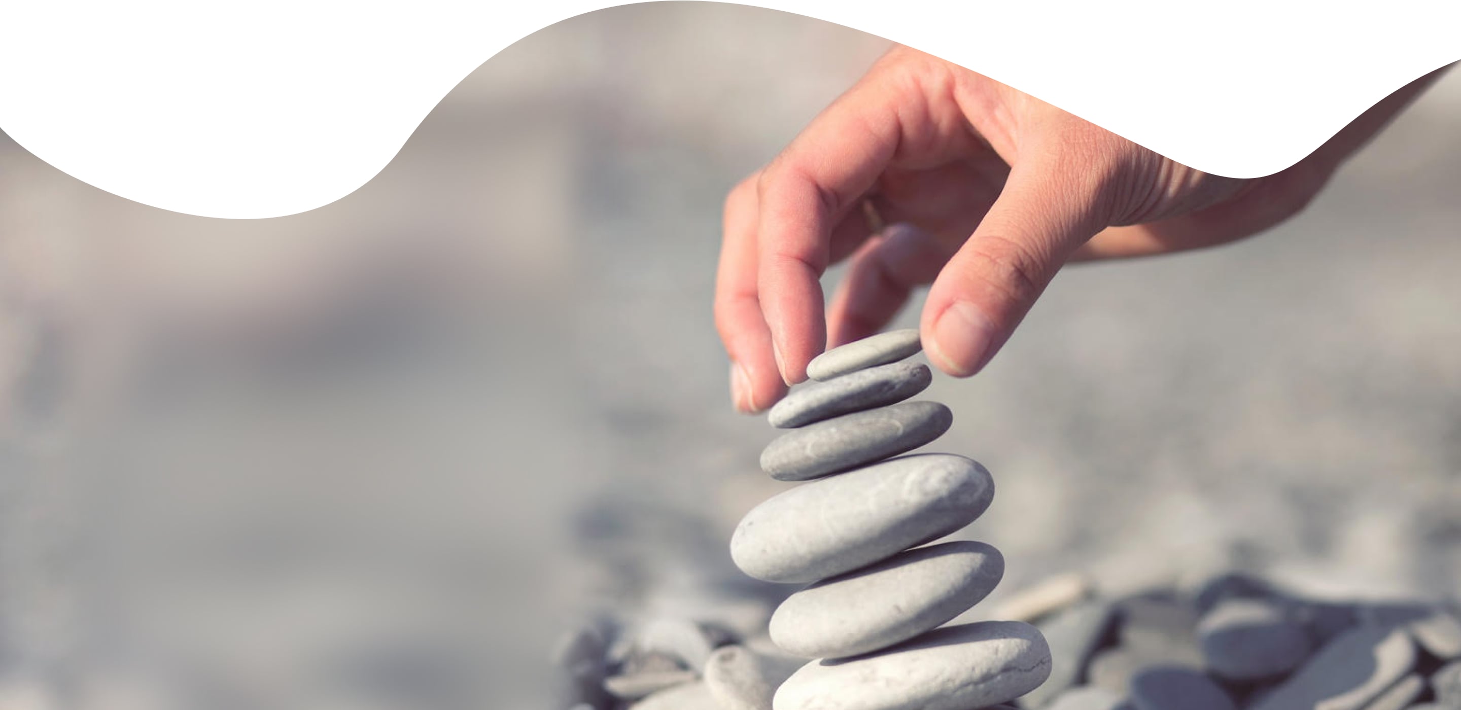 A hand placing a stone onto a cairn in Roojoom’s company photograph