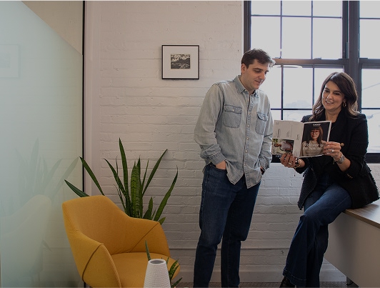 Two Root3 colleagues talking beside a yellow chair in the Chicago office