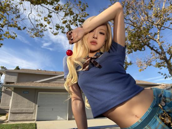 ROSÉ posing outdoors in a blue shirt and jeans