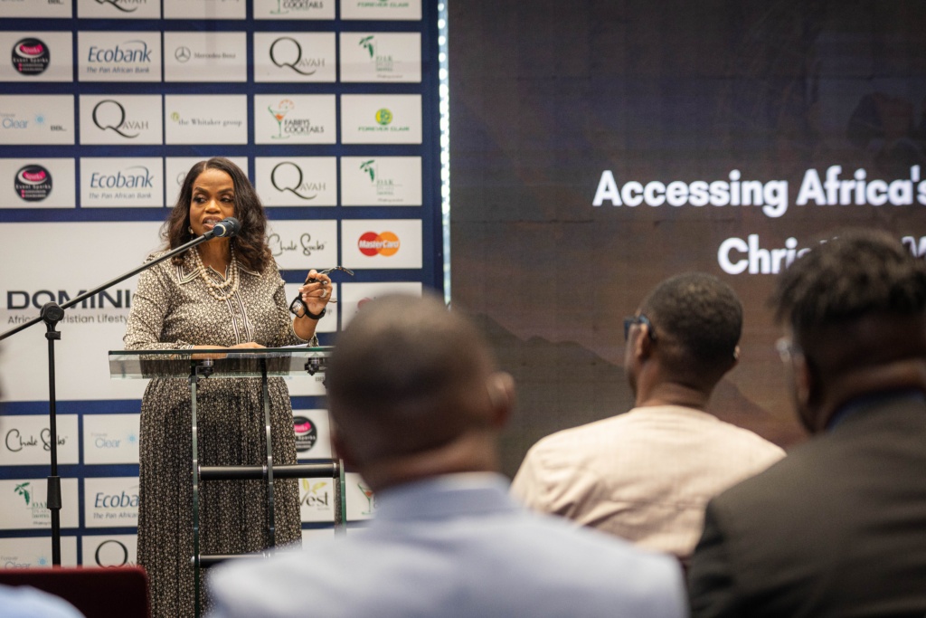 Rosa Whitaker speaks at a lectern during Dominion Television’s Accra forum, with audience members in the foreground.