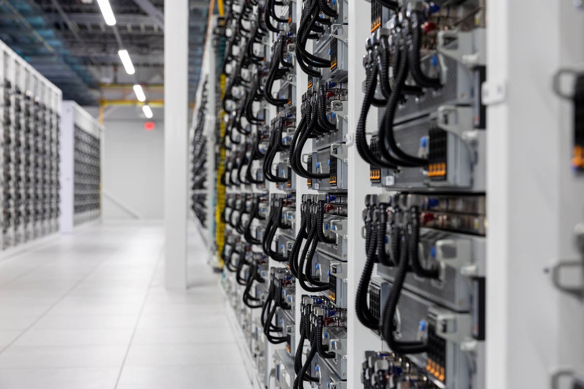 Rows of liquid-cooled GPU racks inside xAI’s Colossus compute hall
