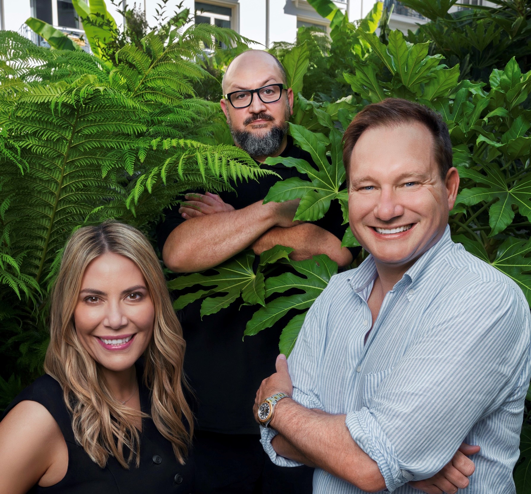 Manifest leaders Melissa Bouma, Steve Slivka and Ross Shelleman standing together among large green plants
