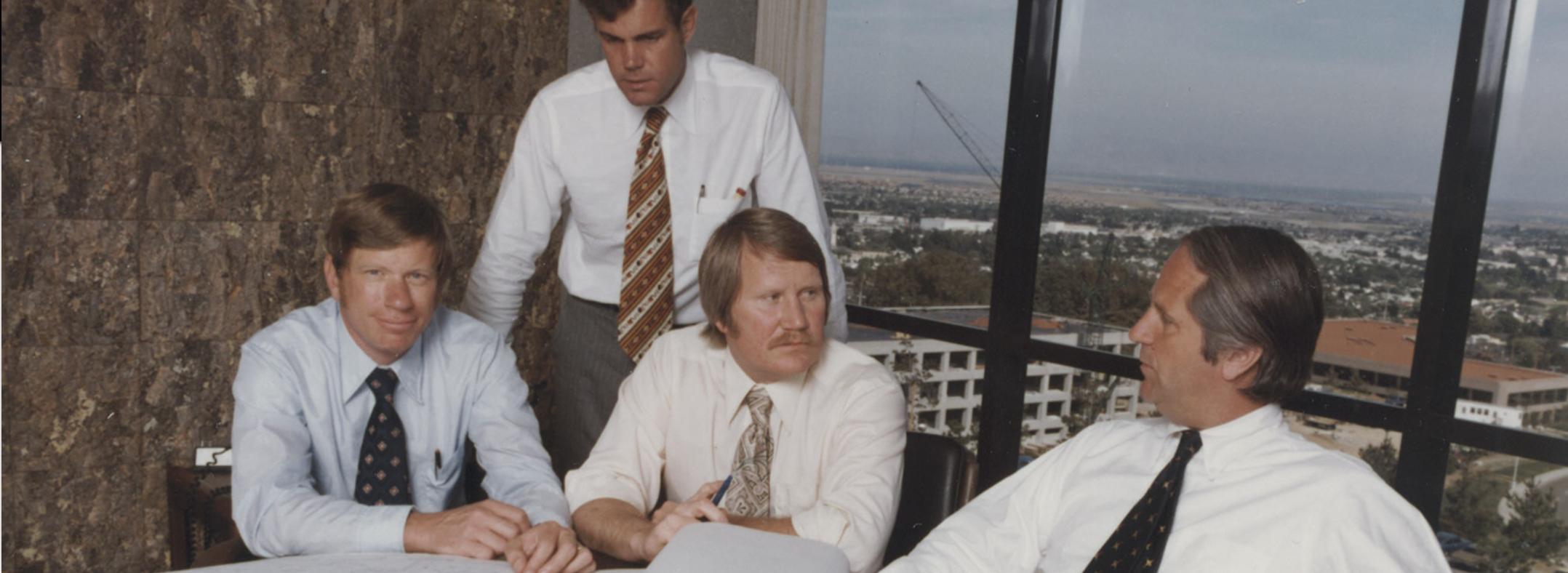 Webcor's four founders gathered around a table, with Ross Edwards seated at the left
