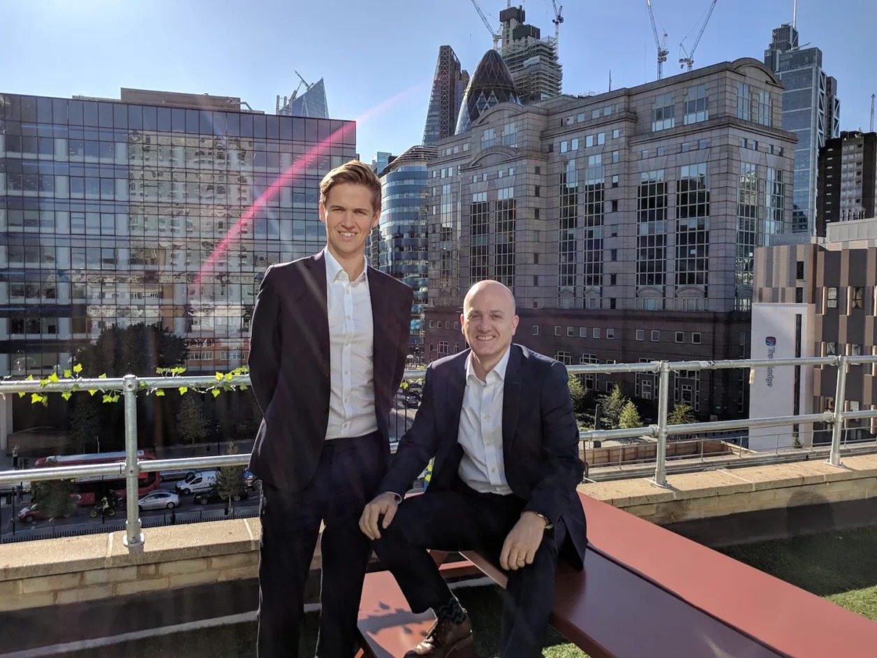 Rota co-founder Tom Williams and former chief executive Stephen Segel seated in front of a Rota sign