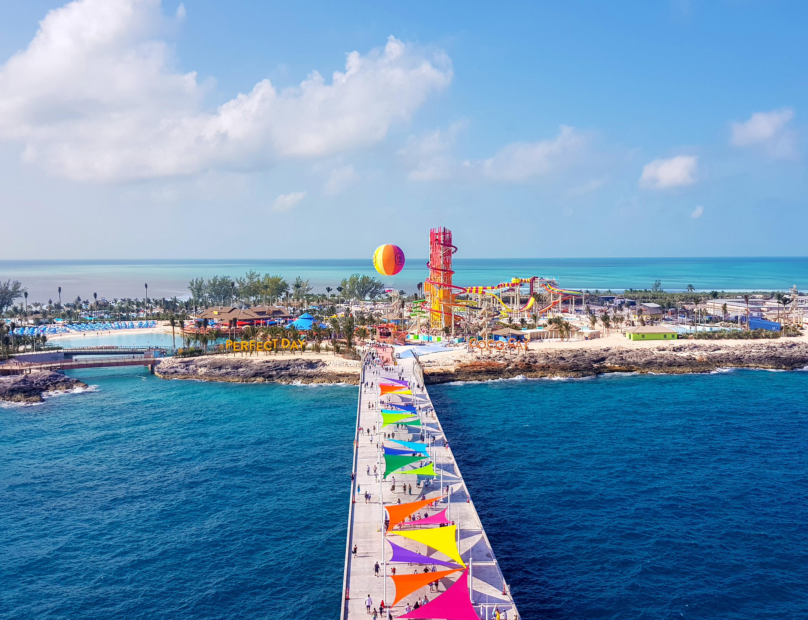 The colorful pier leading into Perfect Day at CocoCay, with beaches, a balloon and water slides beyond
