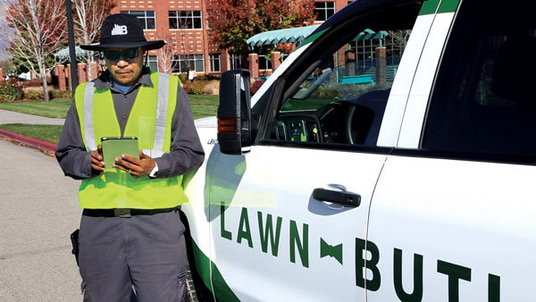 A Lawn Butler worker using a tablet beside a company truck