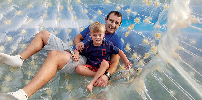 Rudy Larsen and his son smiling inside a transparent inflatable