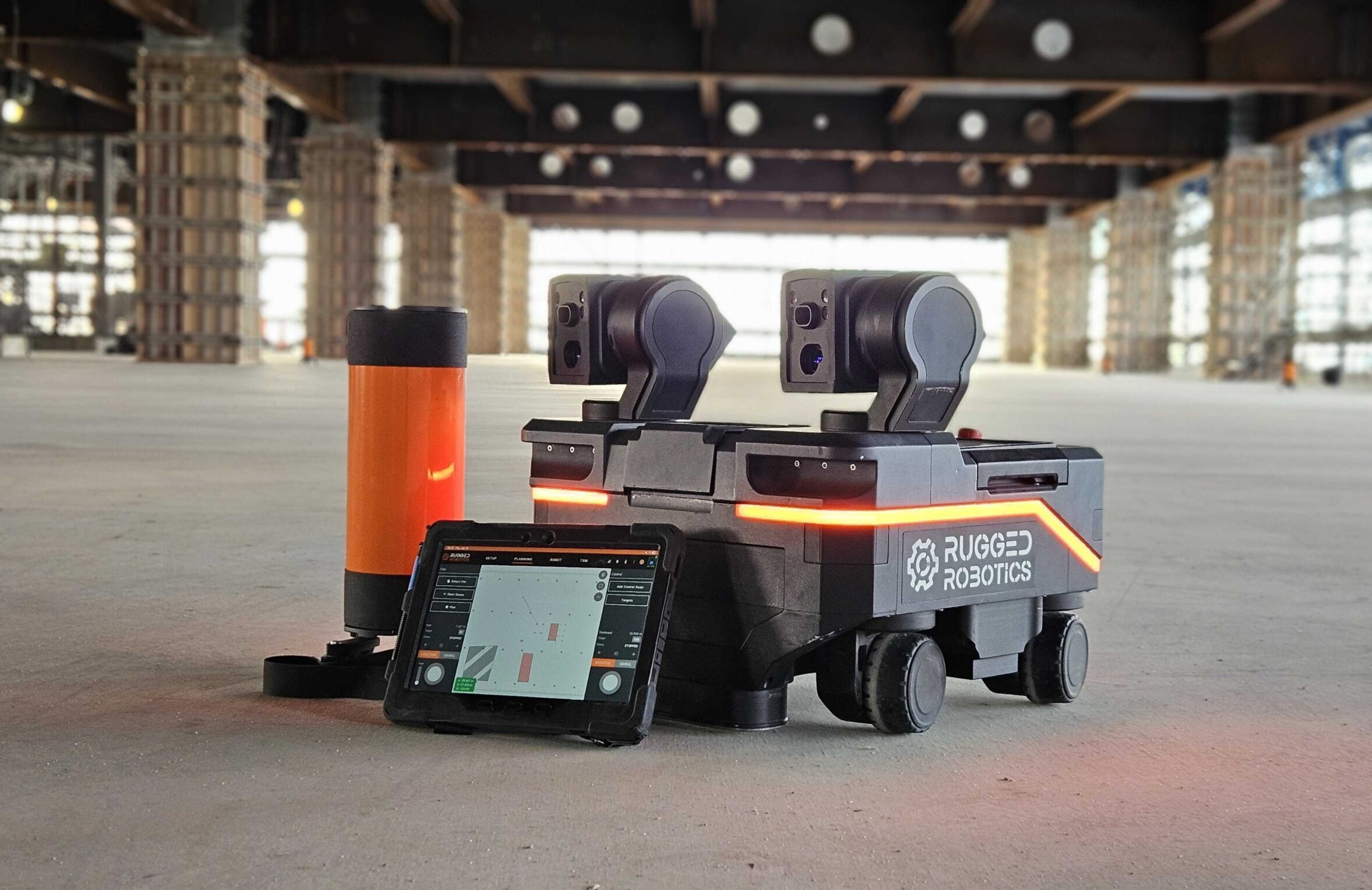 Rugged Robotics layout robot beside a tablet on an unfinished construction floor