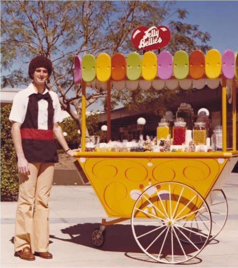 A young Russell Kern standing beside a yellow Jelly Belly pushcart