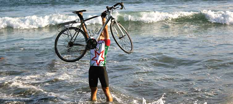 Russell York holding his bicycle overhead in the Pacific Ocean at the end of his cross-country ride