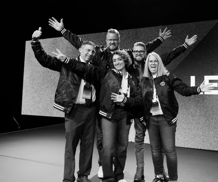Ryan Anderson at left, giving a thumbs-up alongside a group on a Filevine event stage.