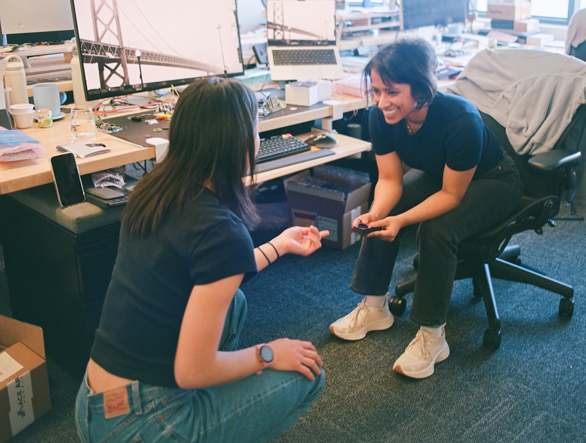 Two Sesame team members talking at a workbench in the office