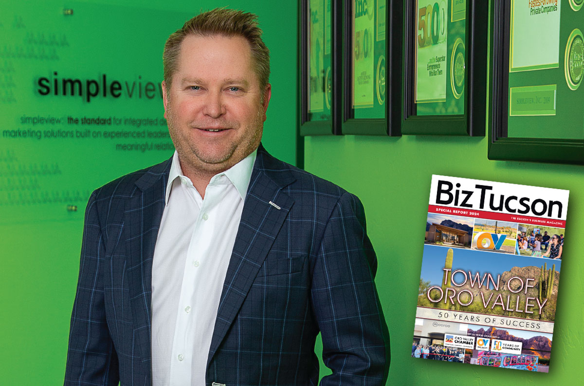 Ryan George in Simpleview’s office, standing beside framed company awards