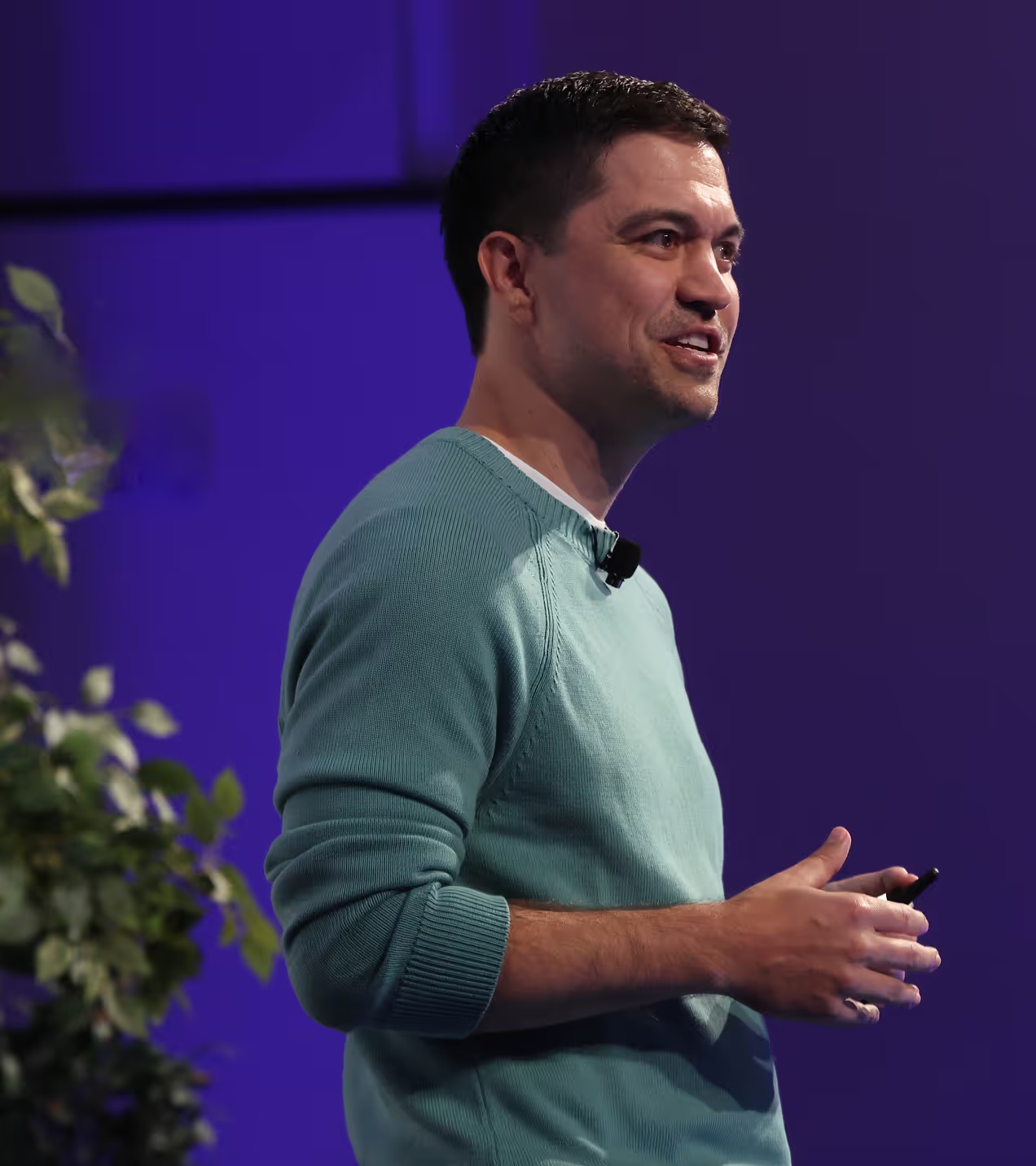 Ryan Glasgow speaking, wearing a green sweater and holding a presentation remote