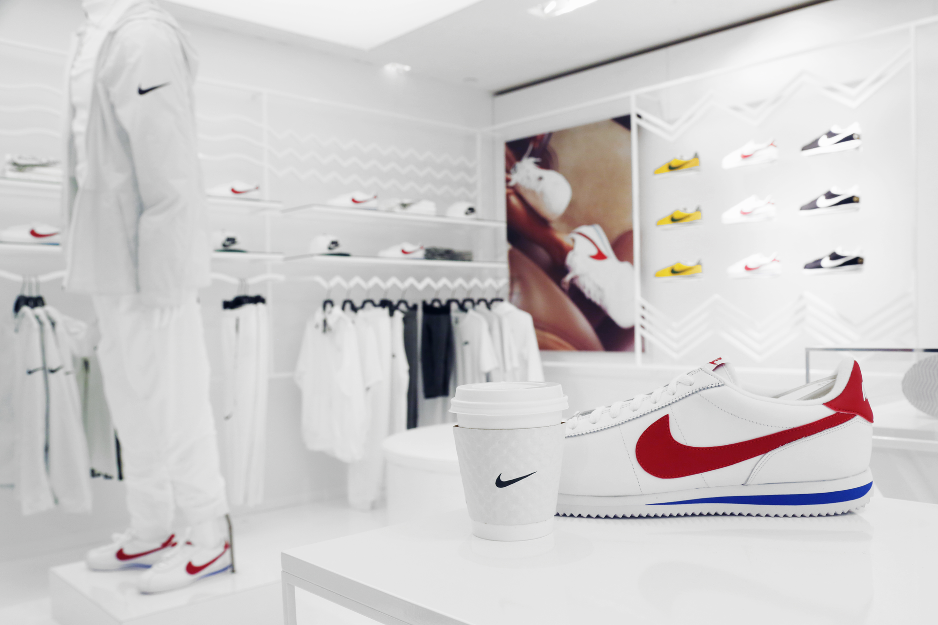 A Nike-branded coffee cup beside a red-and-white sneaker inside a Nike store