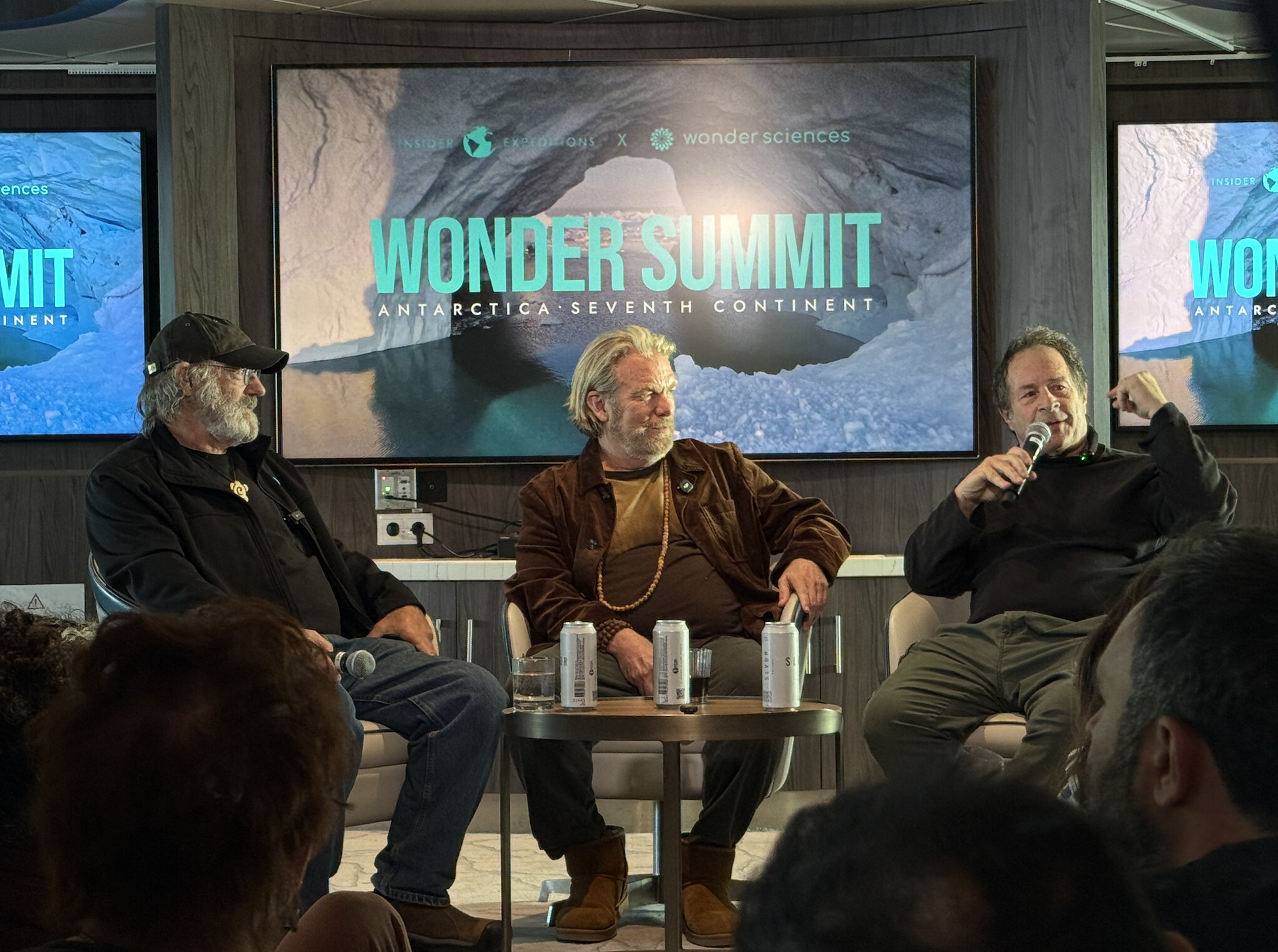 Three speakers seated with microphones at Wonder Summit aboard the Antarctic expedition vessel