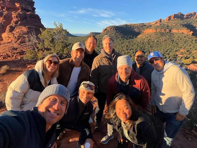 Tide Rock executive team posing together among red rock formations during a mountain retreat