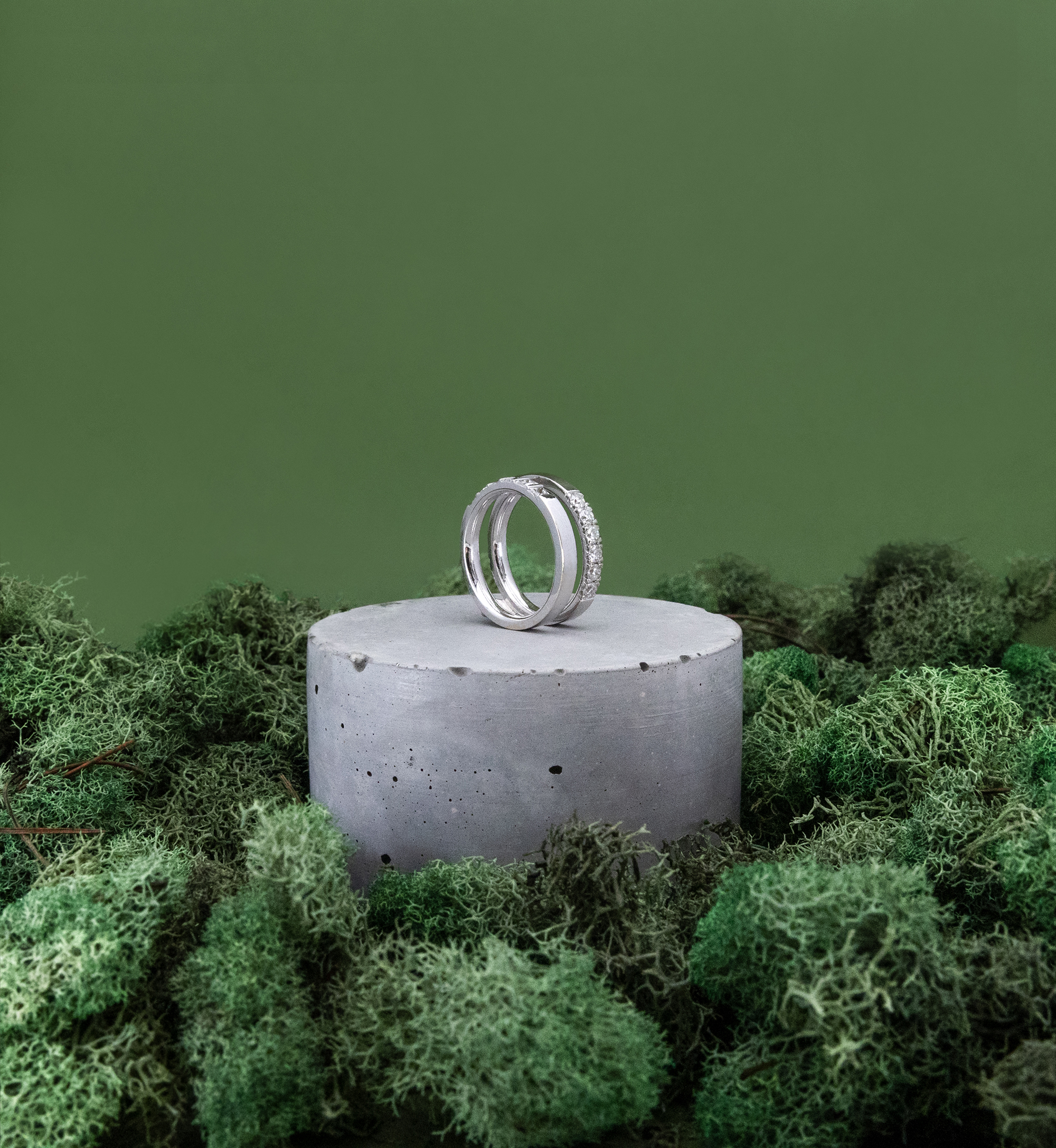An Aether diamond ring on a cylindrical stand surrounded by green moss