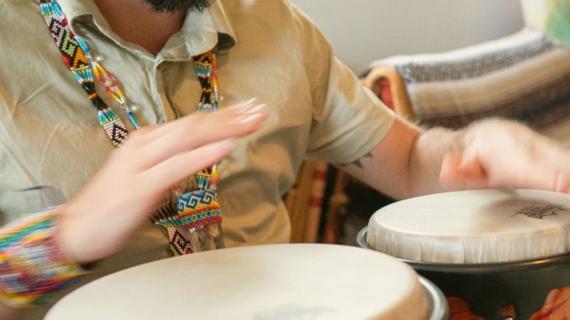 A Rythmia ceremony facilitator playing hand drums
