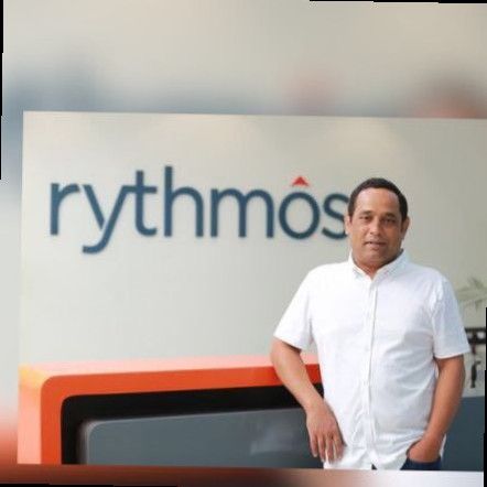 Surender Kantareddy standing beside Rythmos signage