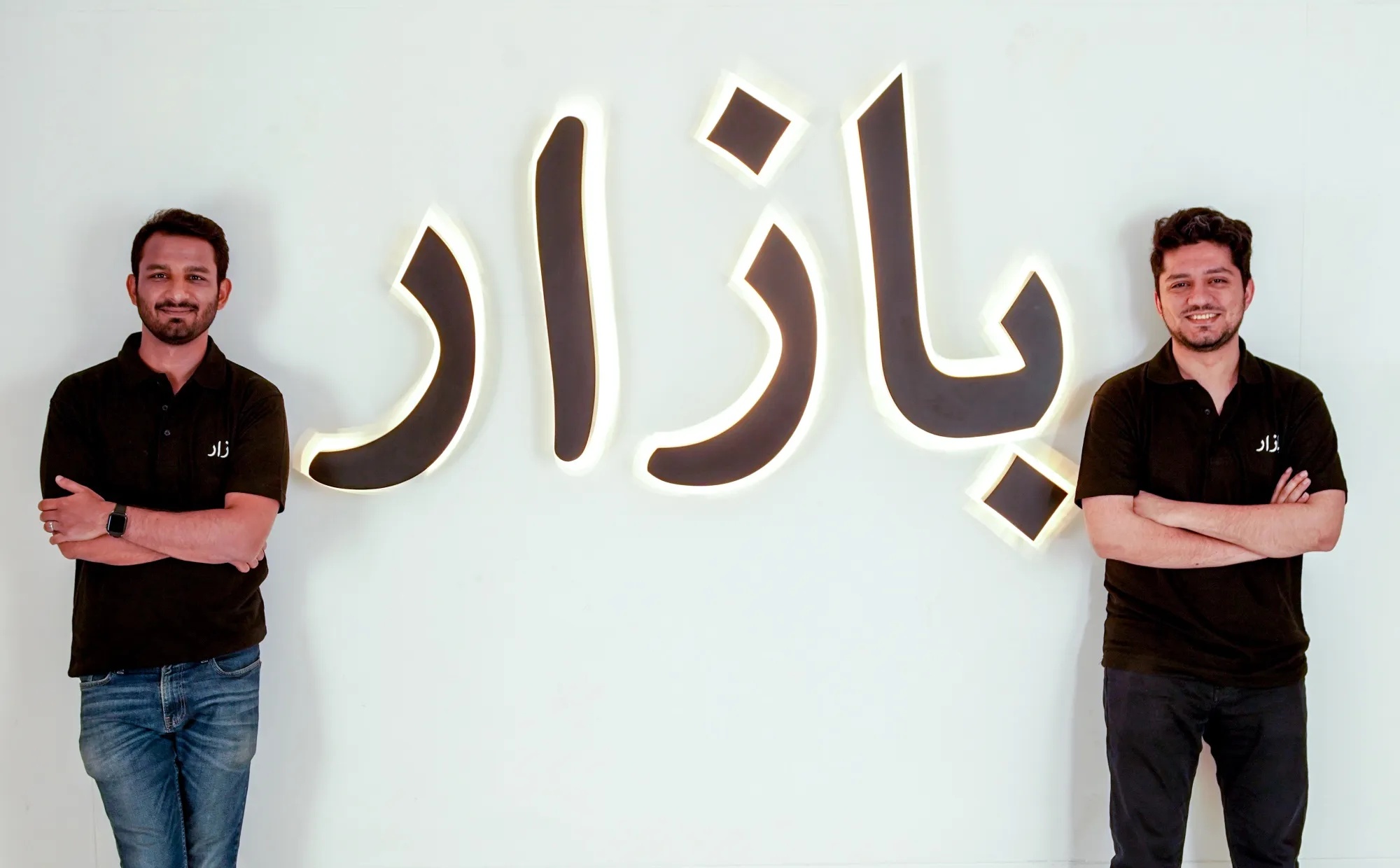 Bazaar co-founders Hamza Jawaid, left, and Saad Jangda, right, beside the illuminated Bazaar name
