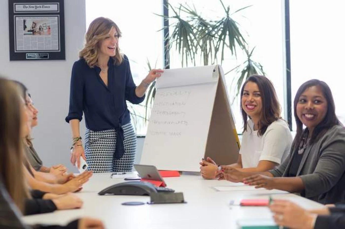 Sabina Gault standing beside a flip chart during an office meeting with colleagues