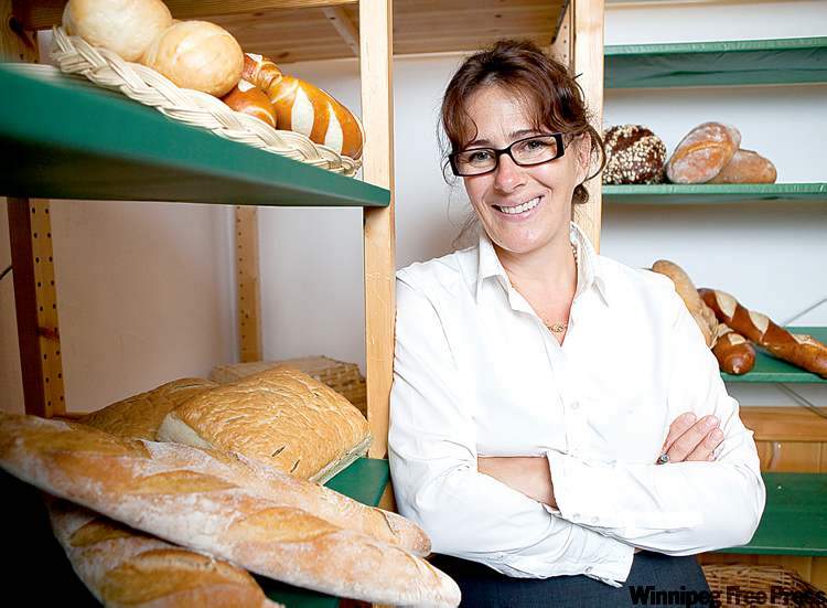 Sabine Veit standing among shelves of bread at her bakery