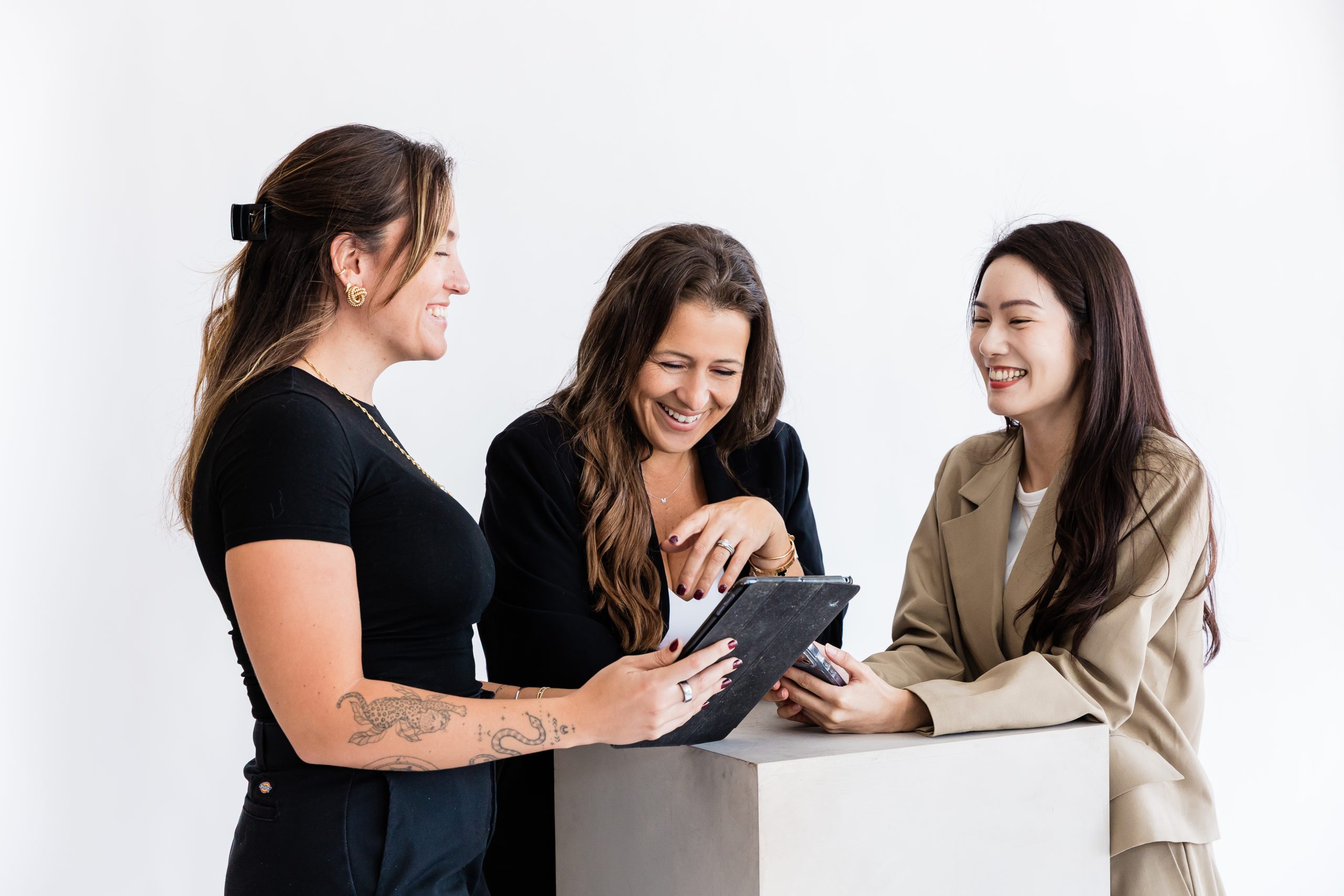 Sabrena Gartland, center, smiling with two colleagues around a tablet in a Frogman branding photograph