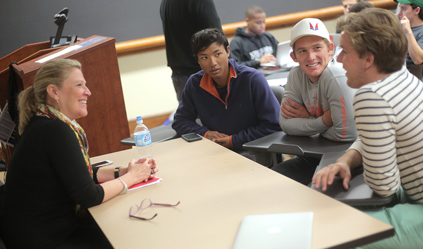 Sabrina Horn seated at a classroom table talking with students at Hobart and William Smith Colleges