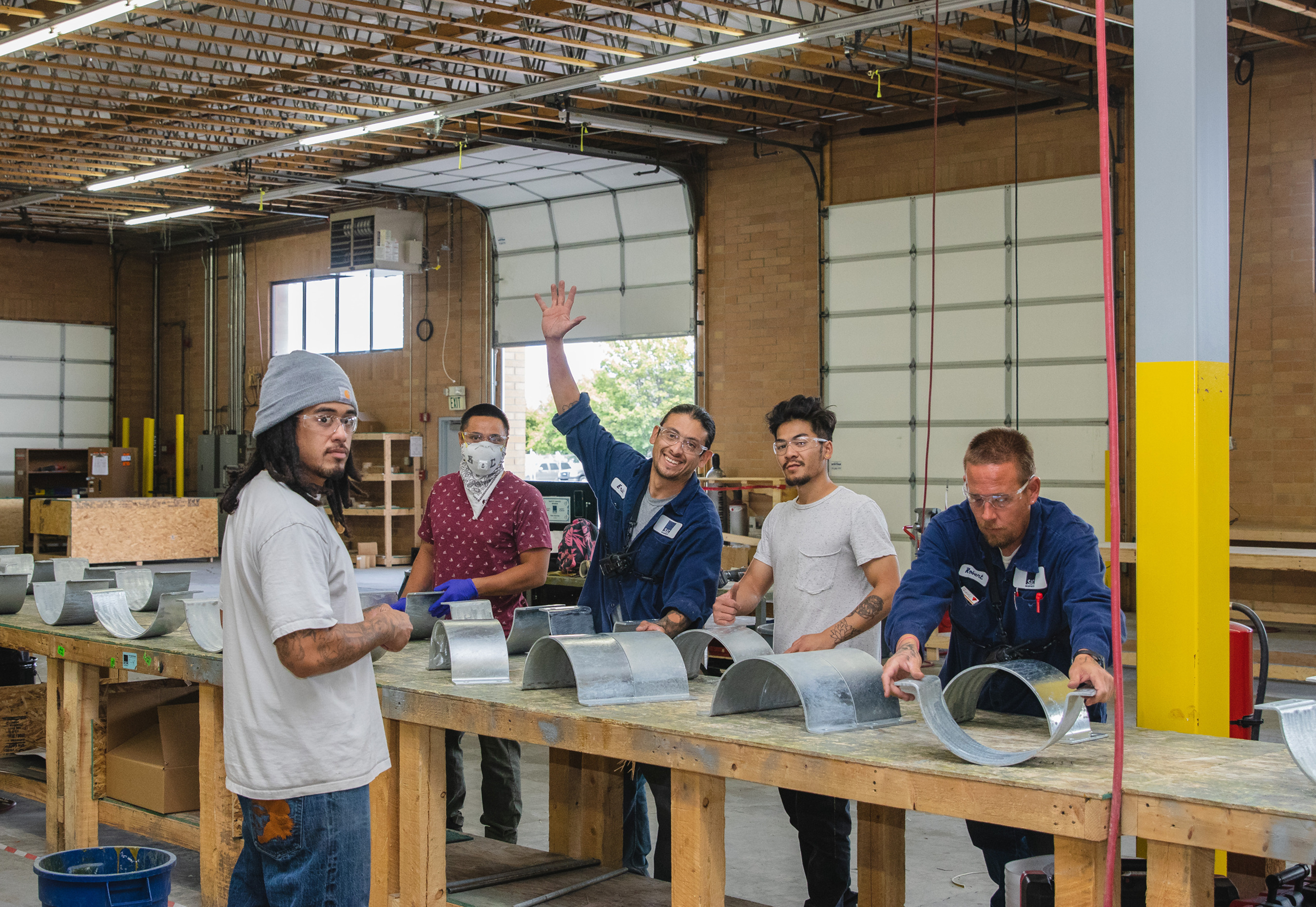 SAC fabrication employees gathered around a workbench with curved metal supports
