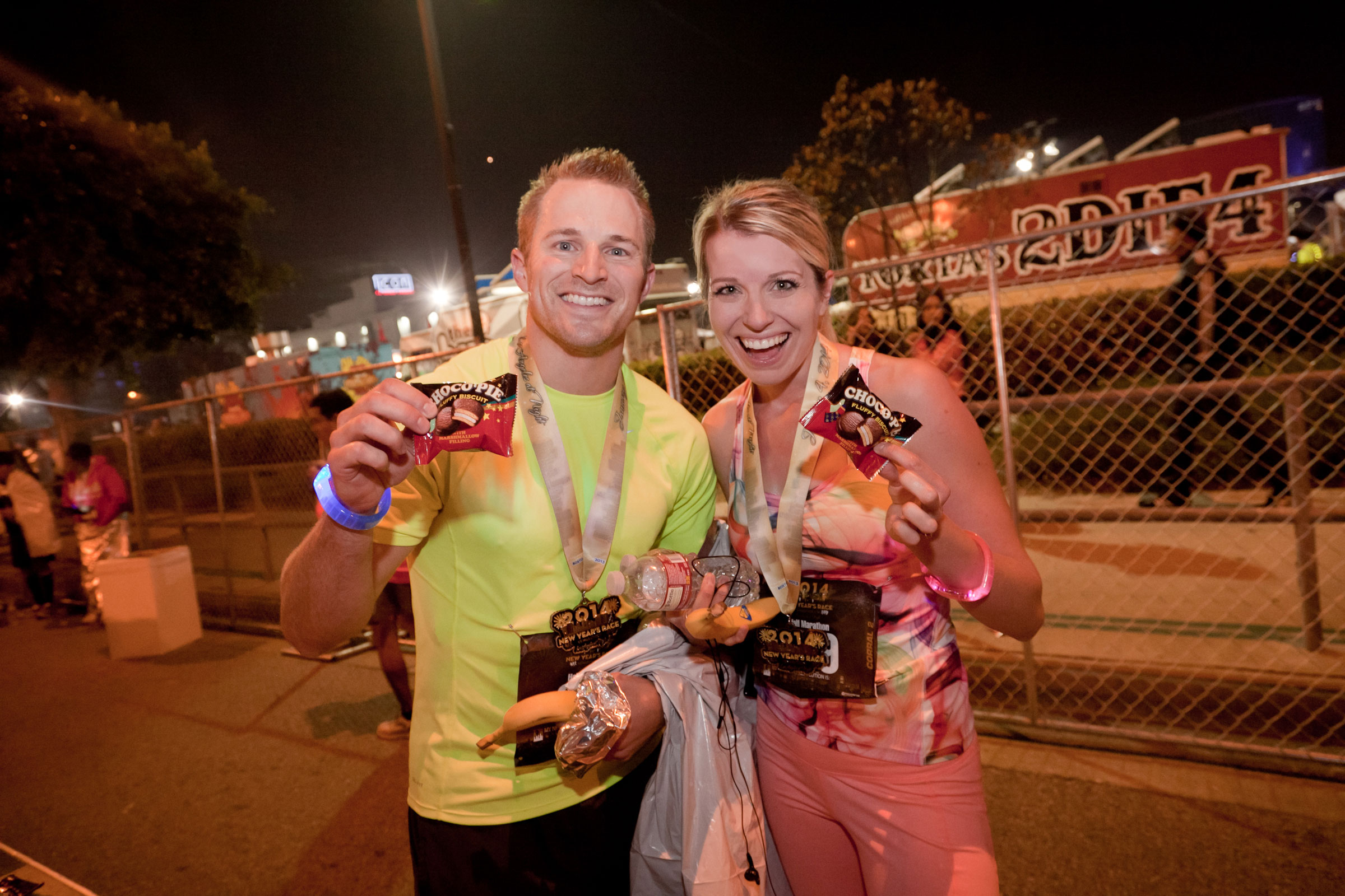 Two runners at a nighttime event holding Orion Choco Pie snacks