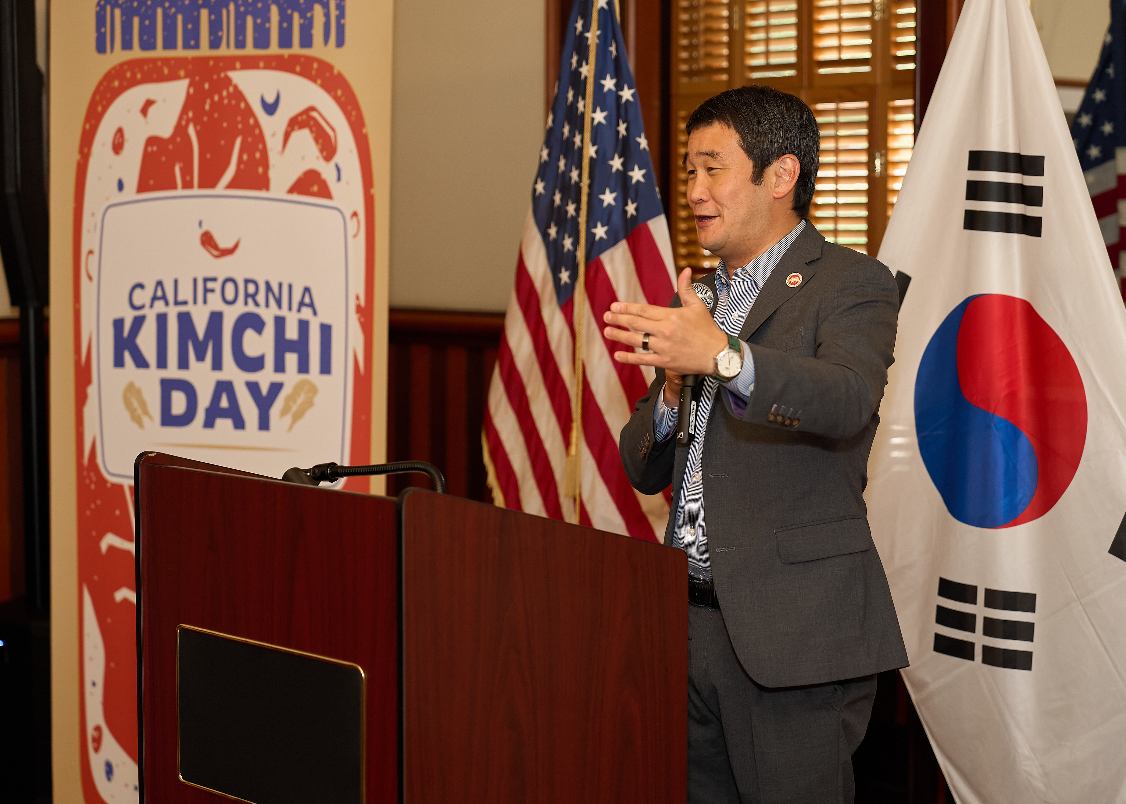 California Senator Dave Min speaking at the 2024 California Kimchi Day event beside United States and South Korean flags