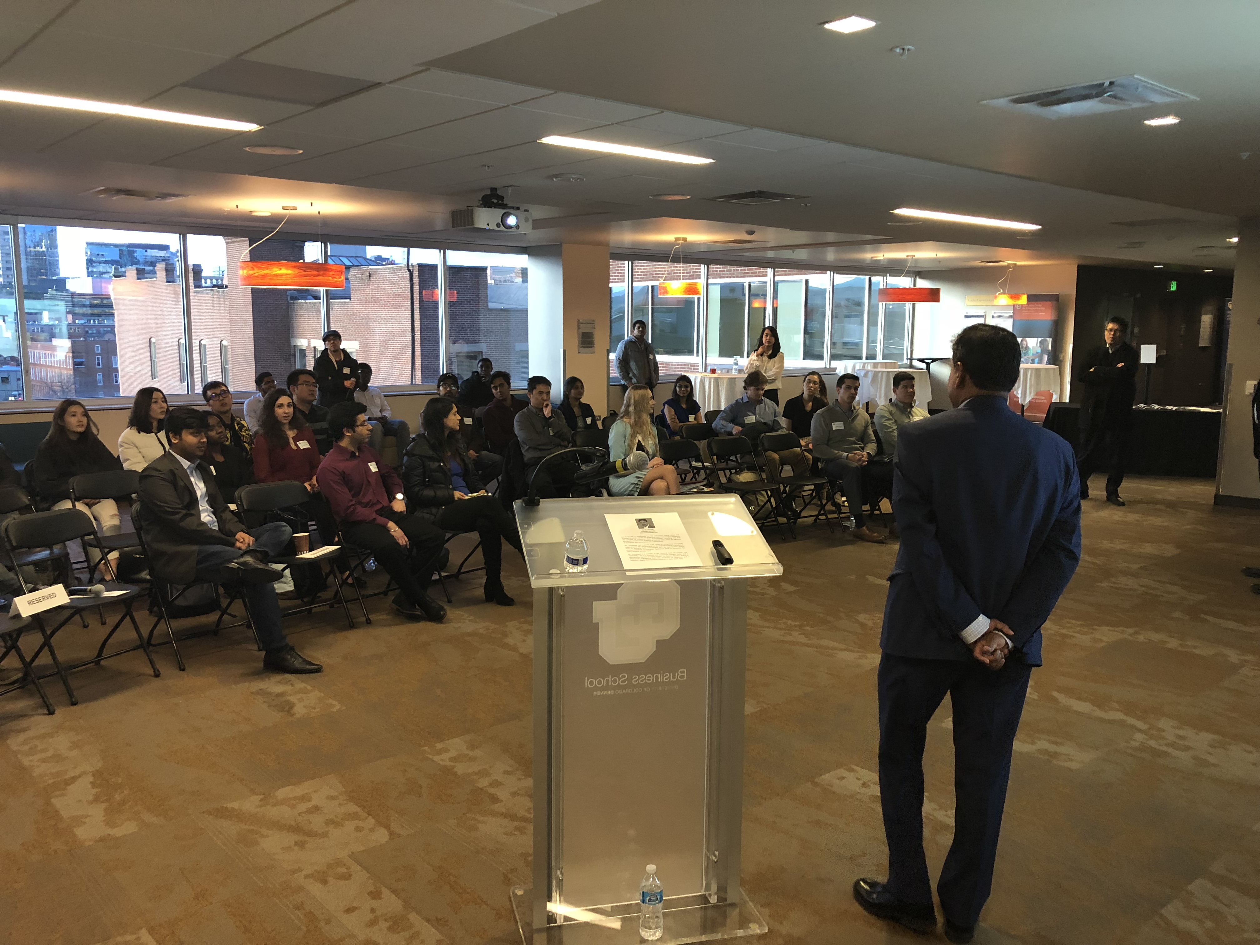 Sai Gundavelli, seen from behind at a lectern, addressing students and faculty at CU Denver.