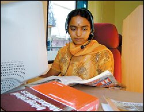 Growing Stars tutor Bindu Sudheep works at a computer in Kochi with a headset, pen mouse and writing tablet.