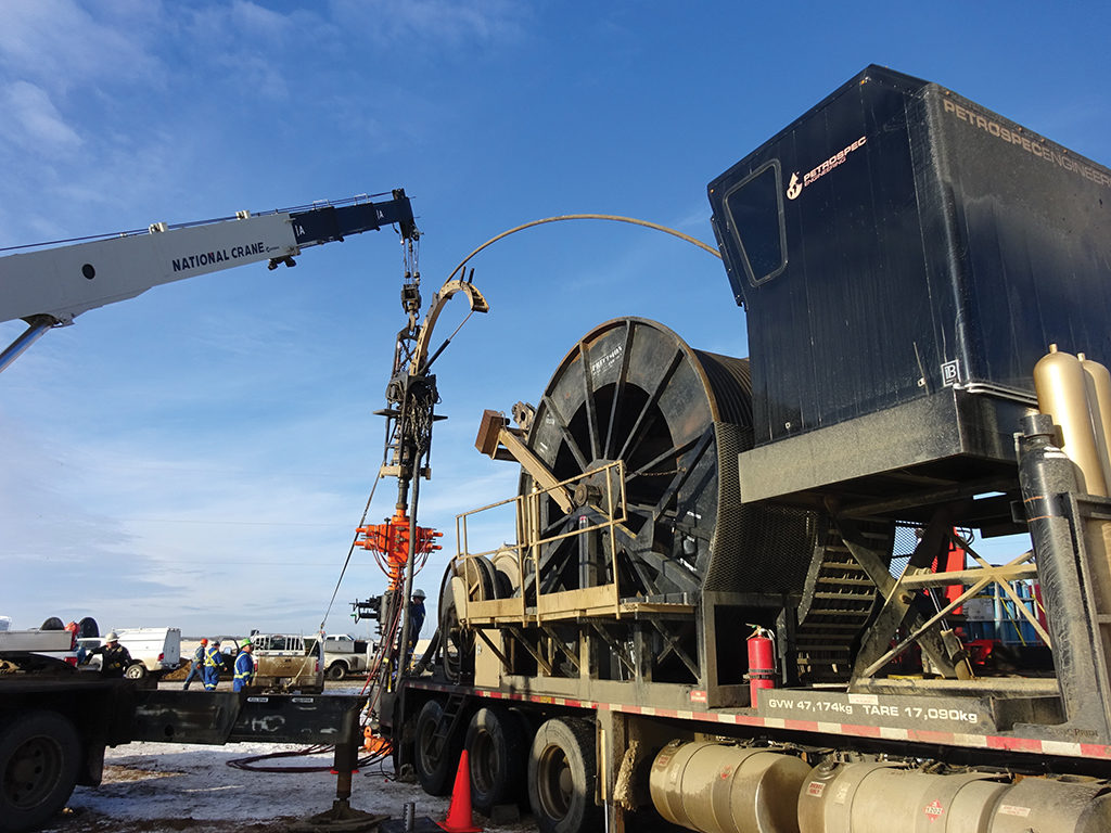 Petrospec coiled-tubing equipment and a crane at an outdoor well site