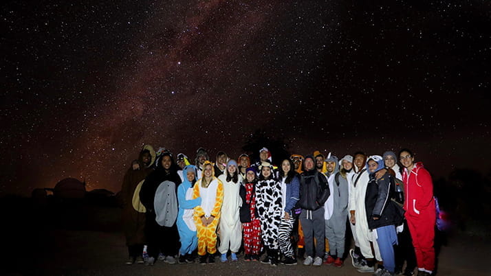 Sam Jactel and fellow Kellogg students posing beneath the stars on their Atacama Desert trip