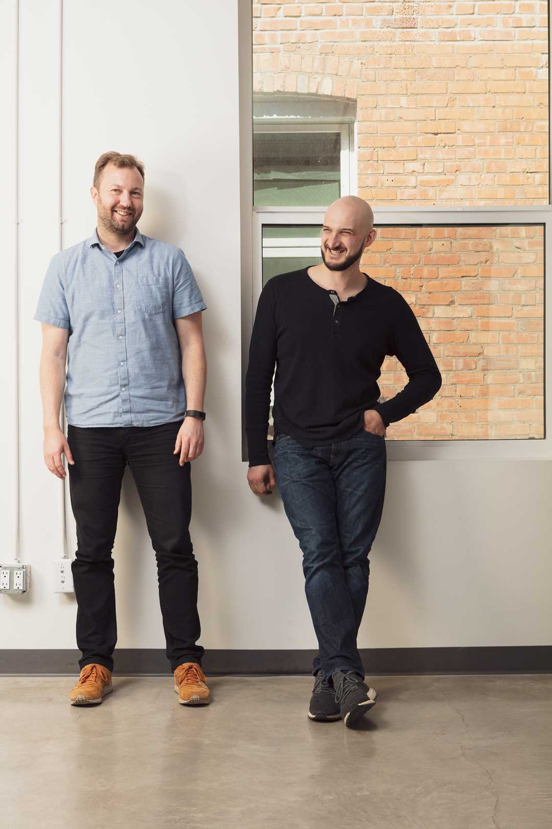 Sam Pillar, left, and Forrest Zeisler standing together in a brick-lined office