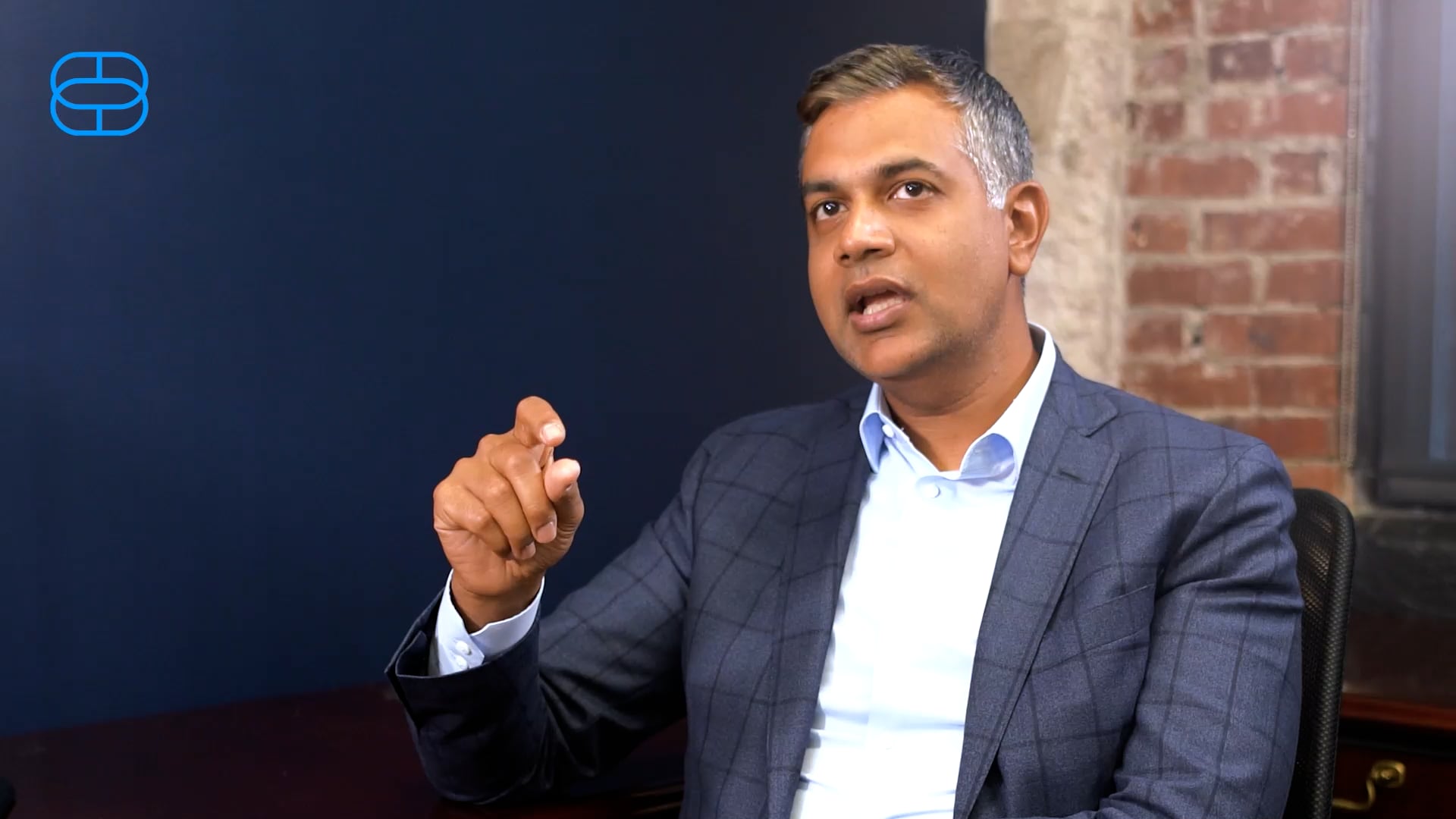 Sam Sidhu gesturing during an interview in a Customers Bank office