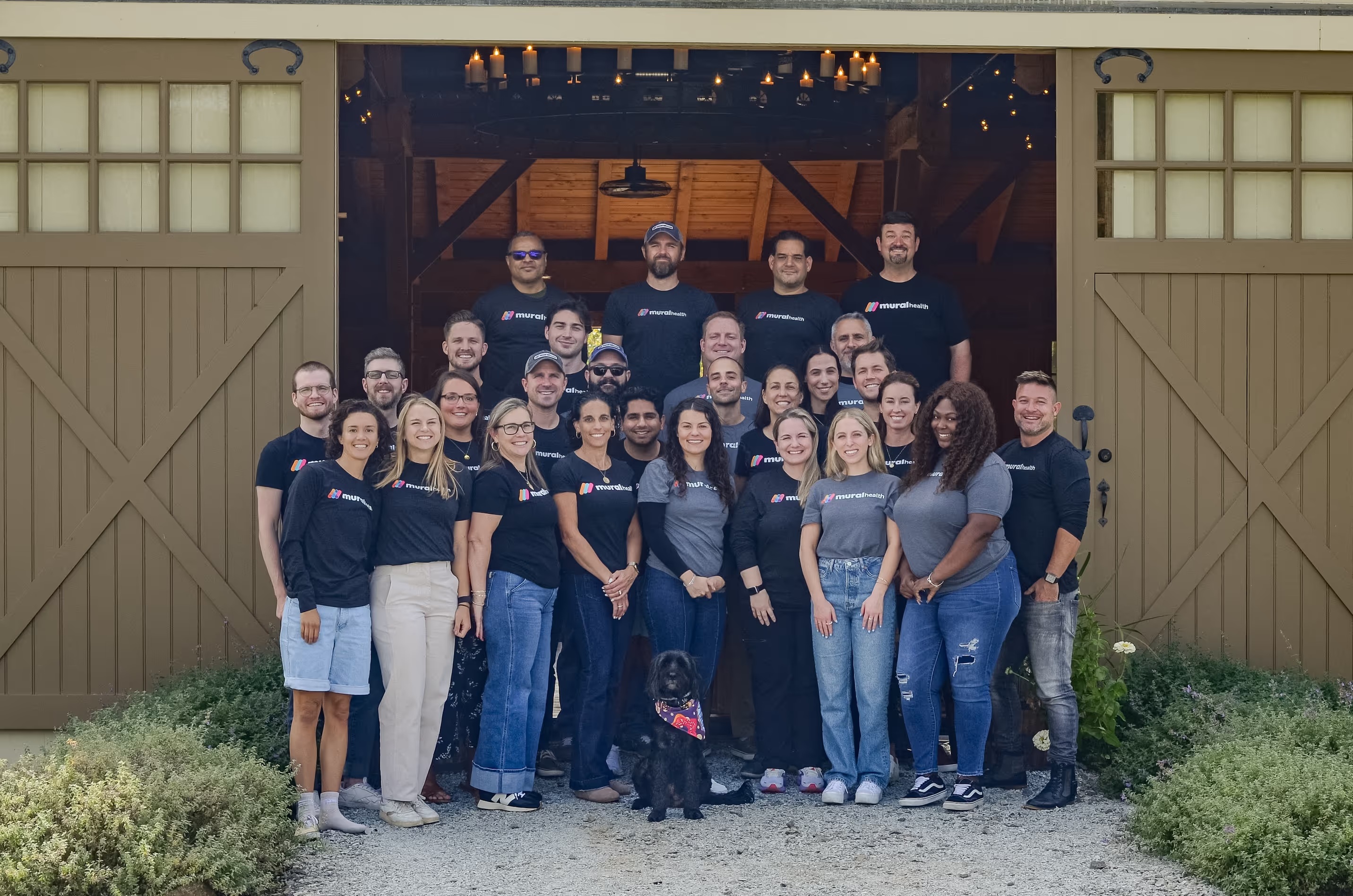 The Mural Health team standing together outside a barn, with a dog in front