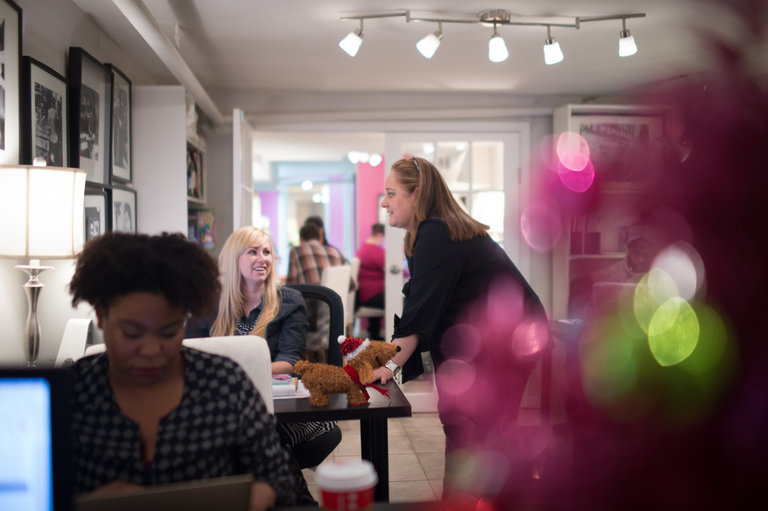 Samantha Martin standing at a desk and talking with colleagues in Media Maison’s office